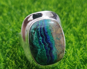 Könnte beinhalten: Ein silberner Ring mit einem grün-blauen Edelstein. Der Edelstein hat ein einzigartiges Muster aus Wirbeln und Linien.