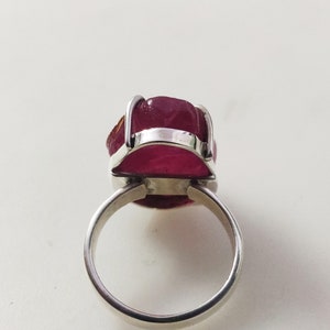 May include: A silver ring featuring a large, faceted, pink gemstone set in a bezel setting.