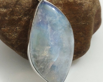 May include: A silver pendant featuring a large, iridescent moonstone in a teardrop shape.