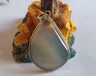 May include: A silver pendant with a light gray agate stone in a teardrop shape.
