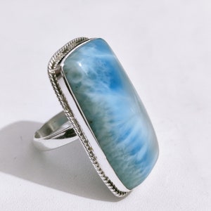 May include: A silver ring with a large, rectangular blue and white gemstone. The gemstone has a swirling pattern.