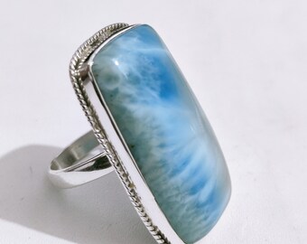 Op de afbeelding: Een zilveren ring met een grote, rechthoekige blauwe en witte edelsteen. De edelsteen heeft een draaiend patroon.