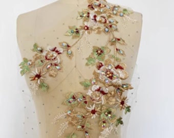 May include: A delicate floral applique with gold, red, and green embroidery and iridescent rhinestones. The applique is on a sheer mesh fabric.