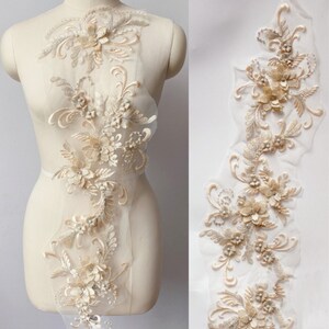 May include: Beige floral lace trim with 3D flowers and pearls. The lace is delicate and intricate, with a soft, romantic feel. It is perfect for adding a touch of elegance to any project.