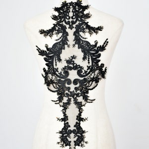 May include: Black lace applique with a delicate floral design. The lace is intricate and detailed, with a variety of shapes and sizes of flowers. The applique is perfect for adding a touch of elegance to any garment.
