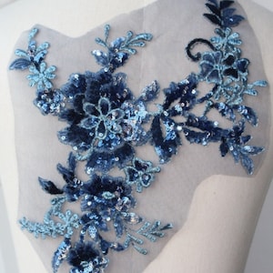 May include: Blue floral applique with sequins and velvet details on a sheer mesh fabric. This embellishment is perfect for adding a touch of elegance to clothing, accessories, or home decor projects.