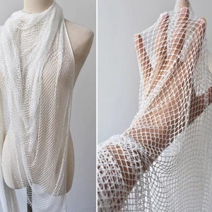May include: White mesh fabric with a fine, even weave. The fabric is draped over a mannequin and held in a hand, showcasing its delicate texture and transparency.