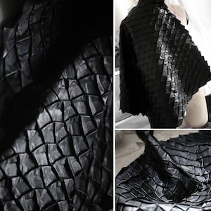 May include: Black leather fabric with a geometric, pleated design. The fabric is textured and has a subtle sheen.