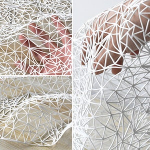 Può includere: Tessuto bianco con un motivo geometrico di triangoli. Il tessuto è flessibile e può essere drappeggiato o piegato.