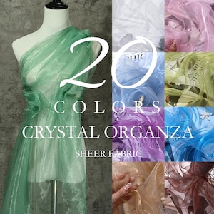 Puede incluir: Una colección de 20 colores de tela de organza de cristal transparente mostrada en un maniquí y en varias muestras. El texto 20 COLORS CRYSTAL ORGANZA SHEER FABRIC está superpuesto en la imagen, mostrando una variedad de opciones textiles.