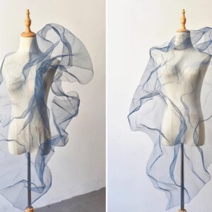 May include: A blue sheer fabric draped over a mannequin. The fabric is gathered and ruffled, creating a soft and flowing look.