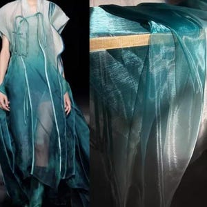 Puede incluir: Una tela transparente con un degradado de turquesa y blanco. La tela es translúcida y tiene un acabado brillante.