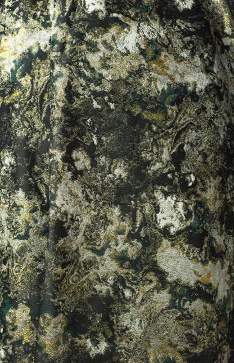May include: Close-up of a fabric with a marbled design. The fabric features a mix of dark green, gold, and silver colors, creating a textured, abstract pattern. The overall effect is luxurious and visually complex, suitable for apparel or home decor.