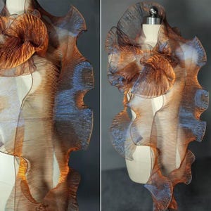 Peut inclure: Un tissu iridescent brun et bleu avec une texture plissée. Le tissu est drapé sur un mannequin.
