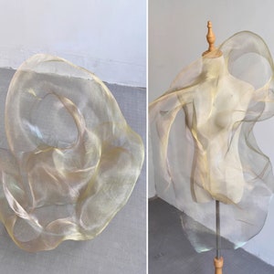 Puede incluir: Una tela de malla dorada drapeada sobre un maniquí. La tela es transparente y tiene una textura delicada y fluida.