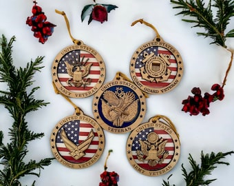 Op de afbeelding: Houten kerstversieringen met patriottische ontwerpen. Elk ornament toont een andere tak van het Amerikaanse leger: Marine, Kustwacht, Luchtmacht en Leger. De ornamenten zijn cirkelvormig en dragen de woorden "United States" en "Veteran".