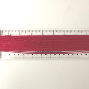 Regla de hilo, herramienta para medir y cortar hilo, ideal para labores de costura.