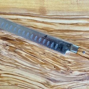 May include: A silver bread knife with a wooden handle engraved with the Hebrew words "Shabbat Shalom".