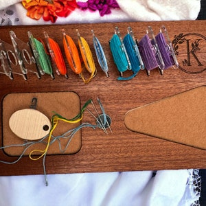 May include: A wooden embroidery organizer with a felt-lined work surface, a compartment for floss bobbins, and a monogrammed initial "K".
