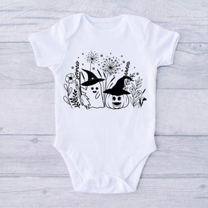 May include: White baby onesie with a black and white illustration of a ghost wearing a witch hat and a pumpkin wearing a witch hat. The ghost and pumpkin are surrounded by black and white flowers and leaves.