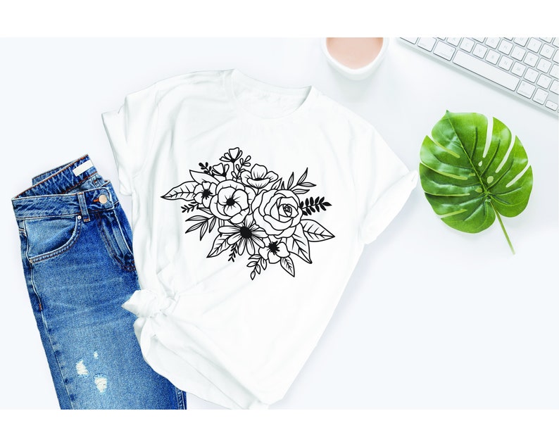 Puede incluir: Una camiseta blanca con un dibujo de l&iacute;nea negra de un ramo de flores. El ramo incluye rosas, flores m&aacute;s peque&ntilde;as y hojas.
