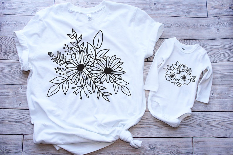 Pu&ograve; includere: Una maglietta bianca e un body bianco a maniche lunghe con un disegno floreale nero. Il disegno presenta due grandi fiori con pi&ugrave; petali e foglie.