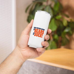 May include: White can cooler with the text "Upon further review the Bears still suck!" in blue and orange lettering.