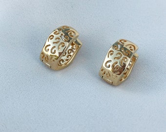 May include: A pair of gold-colored hoop earrings. Each earring has a rectangular shape with a decorative, openwork design. The earrings are displayed on a white surface.