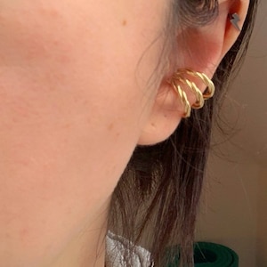 Op de afbeelding: Gouden oormanchet met een gedraaid ontwerp. De oormanchet wordt op het bovenste deel van het oor gedragen.