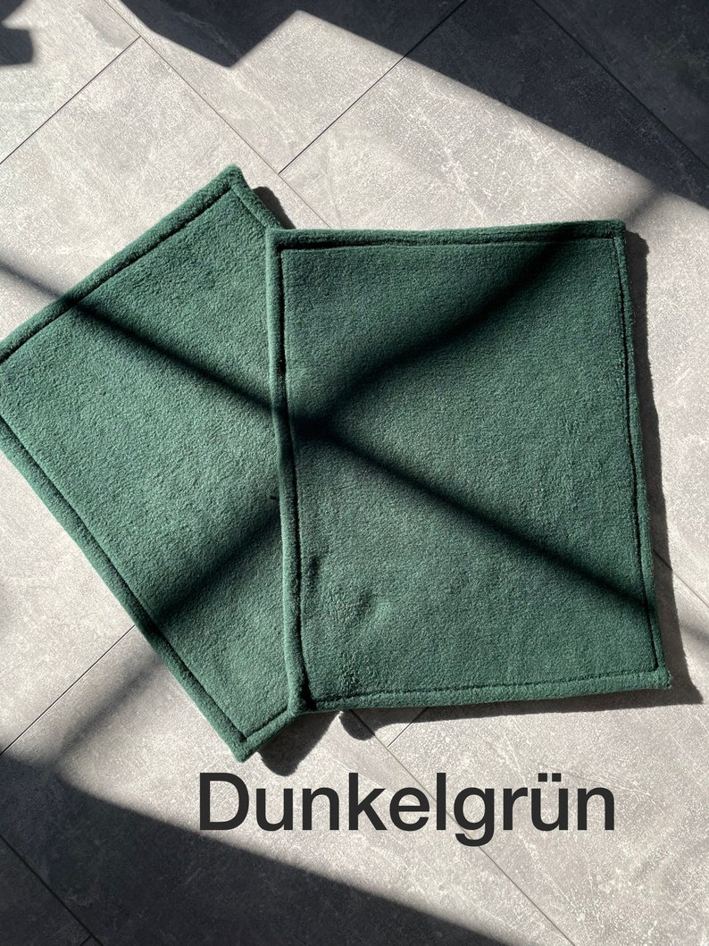 Peut inclure: Deux sets de table rectangulaires en tissu vert fonc&eacute; avec un bord cousu. Les sets de table sont sur un sol en carrelage gris.