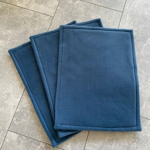 Peut inclure: Trois carr&eacute;s en polaire bleu avec un bord cousu. Les carr&eacute;s sont empil&eacute;s les uns sur les autres.