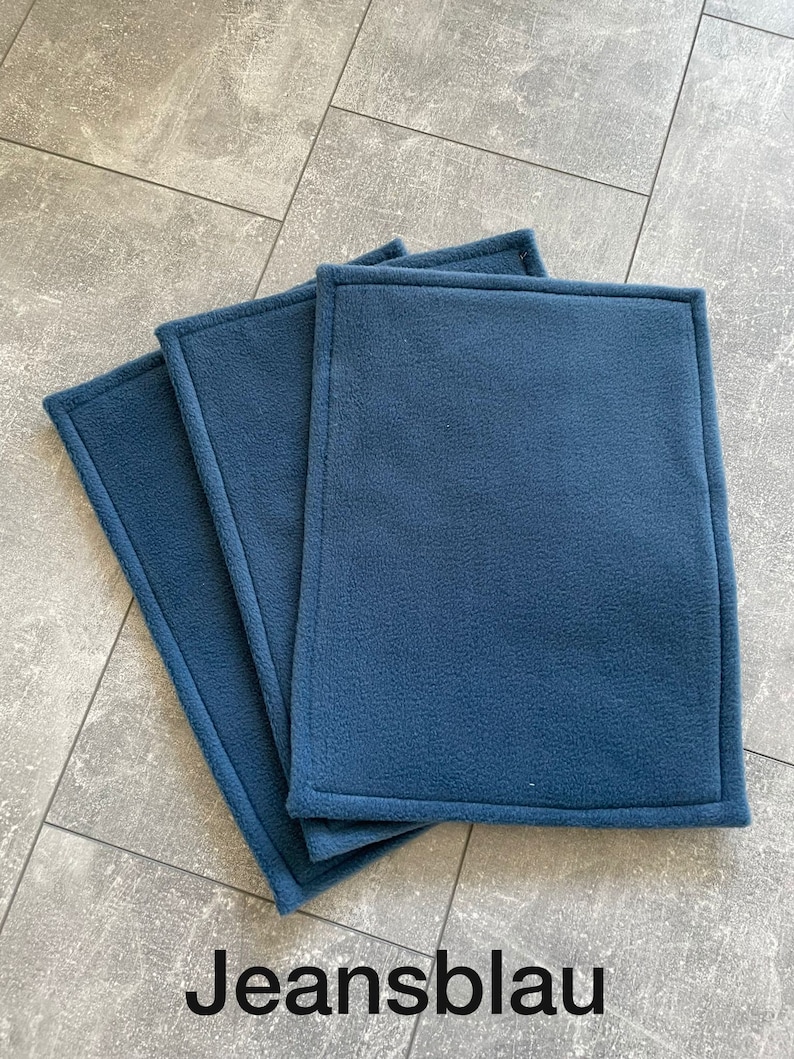Peut inclure: Trois carr&eacute;s en polaire bleu avec un bord cousu. Les carr&eacute;s sont empil&eacute;s les uns sur les autres.