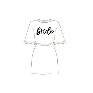May include: White robe with a pink trim and the word "bride" written in black cursive on the back.