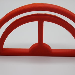 May include: A bright orange plastic semi-circle shape with a smaller semi-circle cut out in the center. The shape has a double rim.