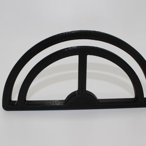 May include: Black plastic semi-circle shape with a smaller semi-circle inside. The shape is a template for creating a curved design.