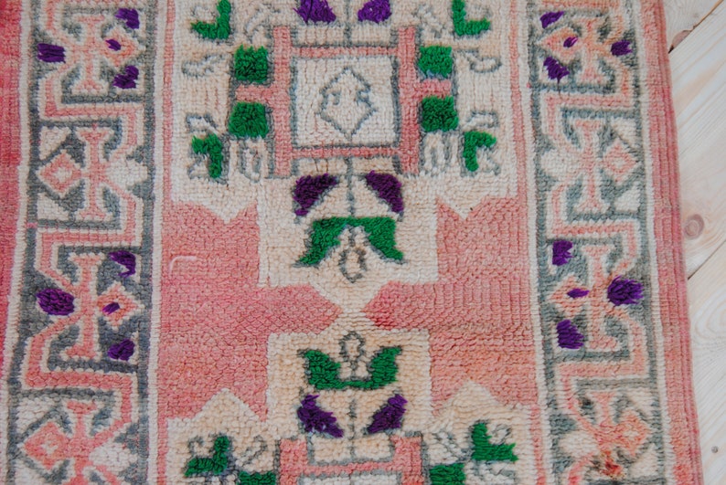 Puede incluir: Una alfombra rosa y crema con un patr&oacute;n geom&eacute;trico en tonos de verde y morado. La alfombra tiene un dise&ntilde;o central con una forma cuadrada y un cuadrado m&aacute;s peque&ntilde;o en el centro.