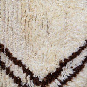 May include: Close-up of a white and brown shag rug with a geometric pattern. The rug has a soft, fluffy texture.