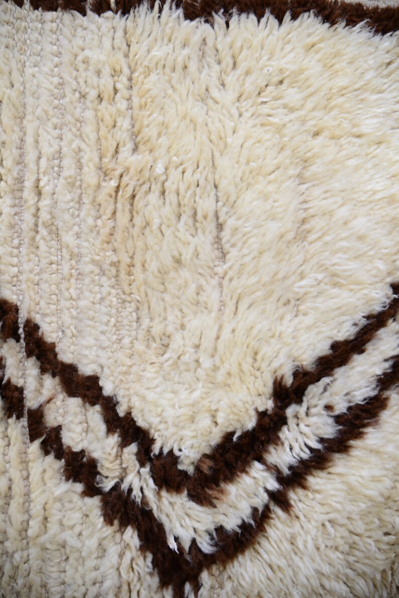 May include: Close-up of a white and brown shag rug with a geometric pattern. The rug has a soft, fluffy texture.