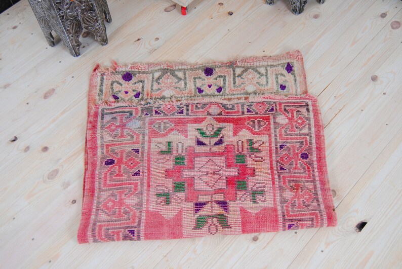 Puede incluir: Una alfombra turca vintage con fondo rojo y intrincados patrones geom&eacute;tricos en tonos de rosa, verde y morado.