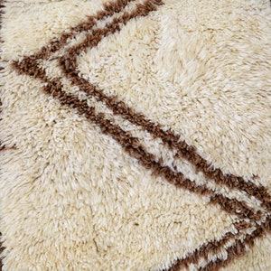 May include: A white and brown shag rug with a geometric pattern. The rug has a soft, fluffy texture.