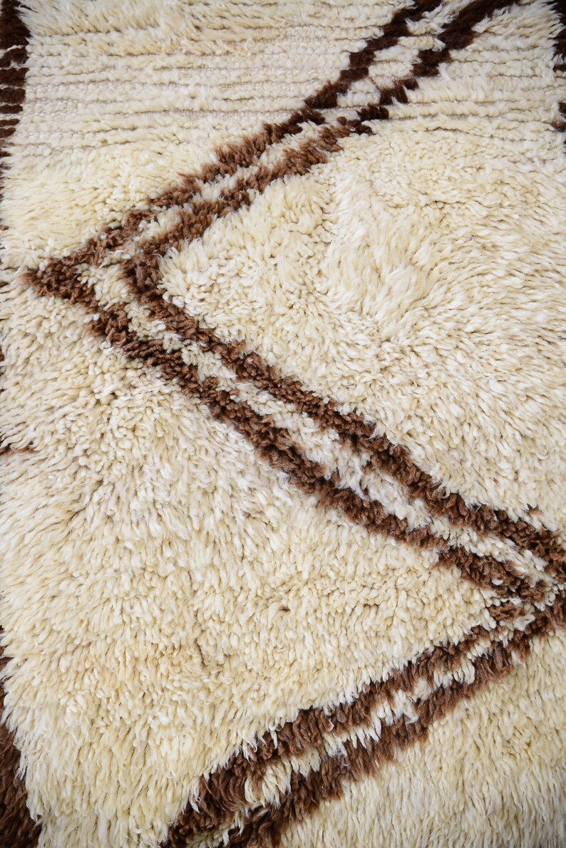 May include: A white and brown shag rug with a geometric pattern. The rug has a soft, fluffy texture.