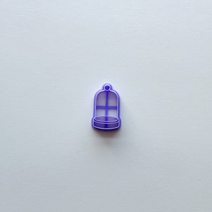 May include: Purple plastic cookie cutter shaped like a birdcage.