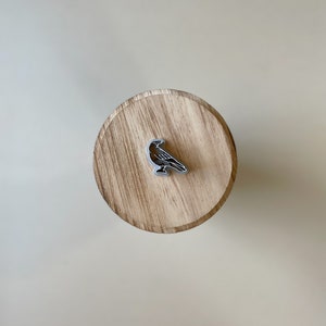 May include: A silver crow cookie cutter on a wooden surface.