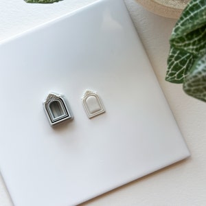 Könnte beinhalten: Zwei weiße, plastikförmige Ausstecher in Form eines Bogens auf einer weißen Oberfläche. Der Ausstecher links ist in drei verschiedenen Größen geschichtet. Der Ausstecher rechts ist ein einzelnes Stück.