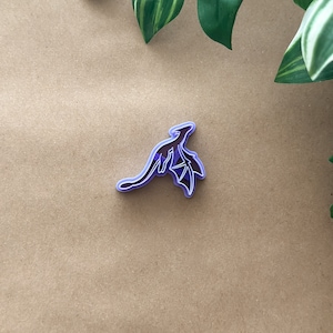 May include: Purple plastic cookie cutter shaped like a dragon with wings outstretched.
