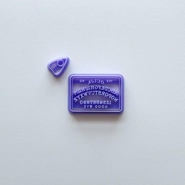 Peut inclure: Emporte-pièces en plastique violet en forme de planche Ouija et d'un planchette. L'emporte-pièce de la planche Ouija comporte les lettres de l'alphabet, les chiffres de 1 à 9, et les mots "GOOD BYE", "1234567890", "YES", "NO", et "OUIJA".