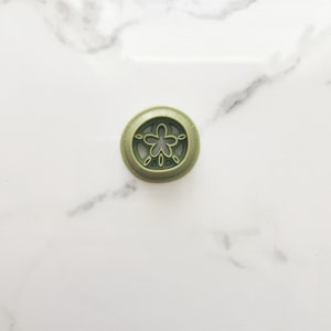 May include: A green plastic bottle stopper with a decorative flower design.