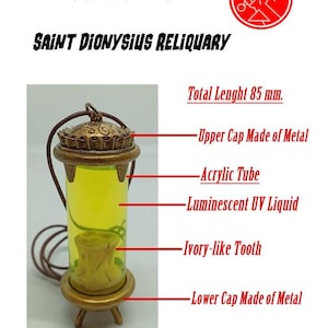 May include: A Hellboy Saint Dionysius Reliquary, 8.5 cm tall. It has metal caps, an acrylic tube with luminescent UV liquid, and an ivory-like tooth. The design includes the text "HELLBOY" and "SAINT DIONYSIUS RELIQUARY".