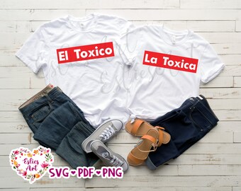 May include: Two white t-shirts with red text. The left shirt says "El Toxico" and the right shirt says "La Toxica". The shirts are laid out on a wooden surface with jeans, sandals, and sneakers.