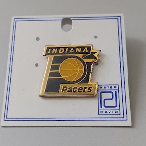 May include: Gold and black Indiana Pacers pin with a basketball and the team's logo. The pin is on a white card with the name "Peter David" printed on it.